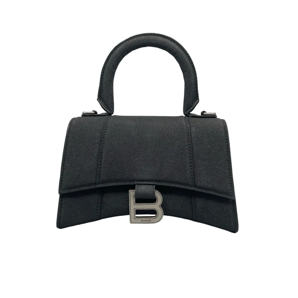 Front view of a Balenciaga Hourglass XS bag in black suede, featuring the signature curved base, top handle, and silver-tone B logo hardware on a white background.