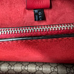 Close-up of a red Gucci bag with a visible logo and zipper.