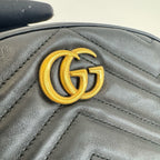 Close-up of a black leather handbag with a gold Gucci logo.