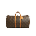 A Louis Vuitton monogram canvas duffel bag with tan leather handles and side straps, shown against a light gray background.