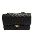 A black quilted flap shoulder bag with gold-tone hardware, featuring a prominent interlocking CC turn-lock and a chain strap, photographed against a neutral light gray background.
