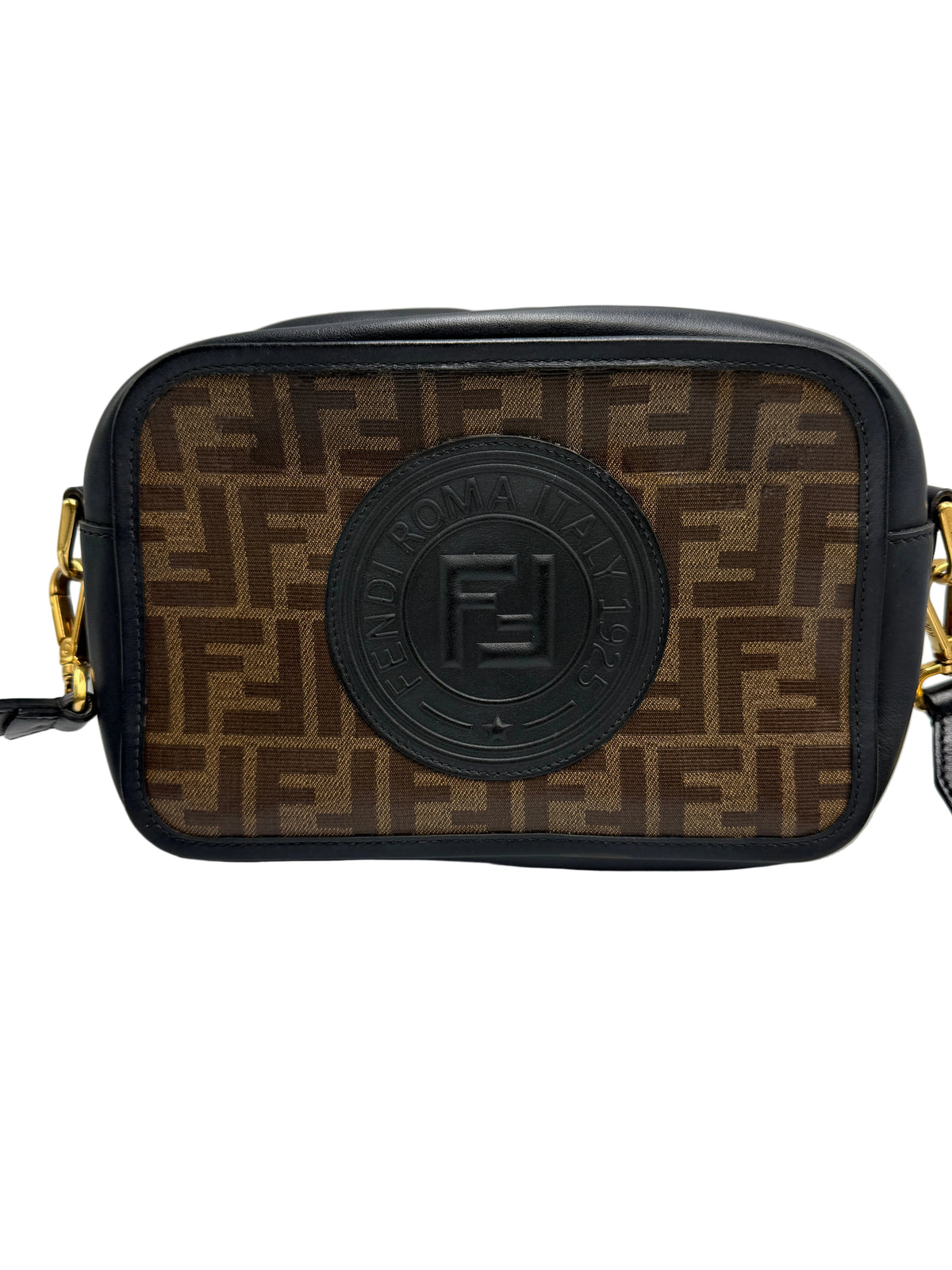 Fendi camera bag in brown Fendi Zucca monogram canvas with black leather trim and a central black embossed logo patch, shown on a light gray background.