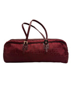 Front view of a vintage Fendi elongated cylindrical barrel shoulder bag in burgundy Zucca monogram canvas with thin leather straps.