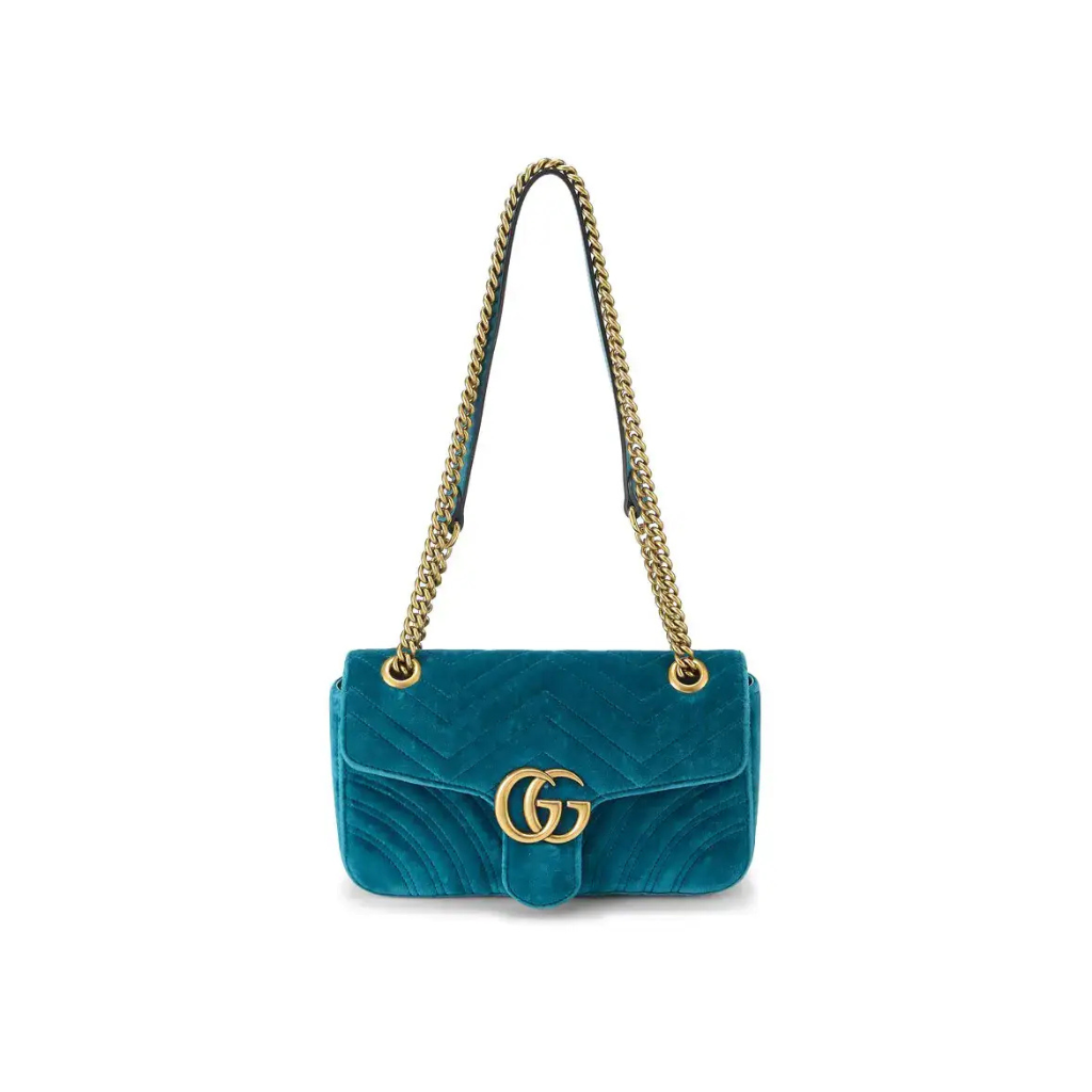A teal velvet shoulder bag with a gold-tone interlocking G logo on the front and a gold chain strap, shown against a plain white background.