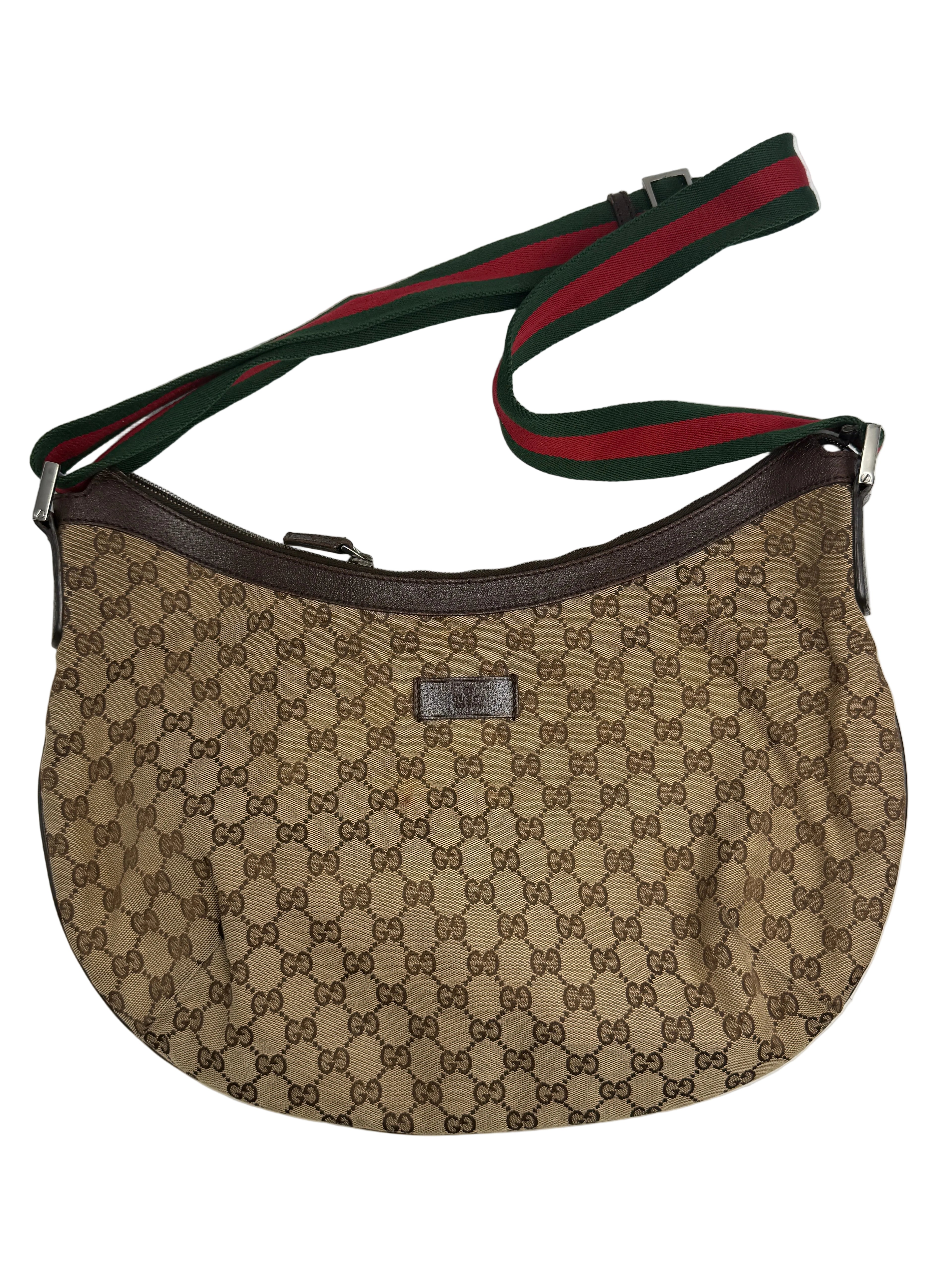 Front view of a Gucci half-moon shoulder bag in GG canvas with green and red Web strap and brown leather trim.