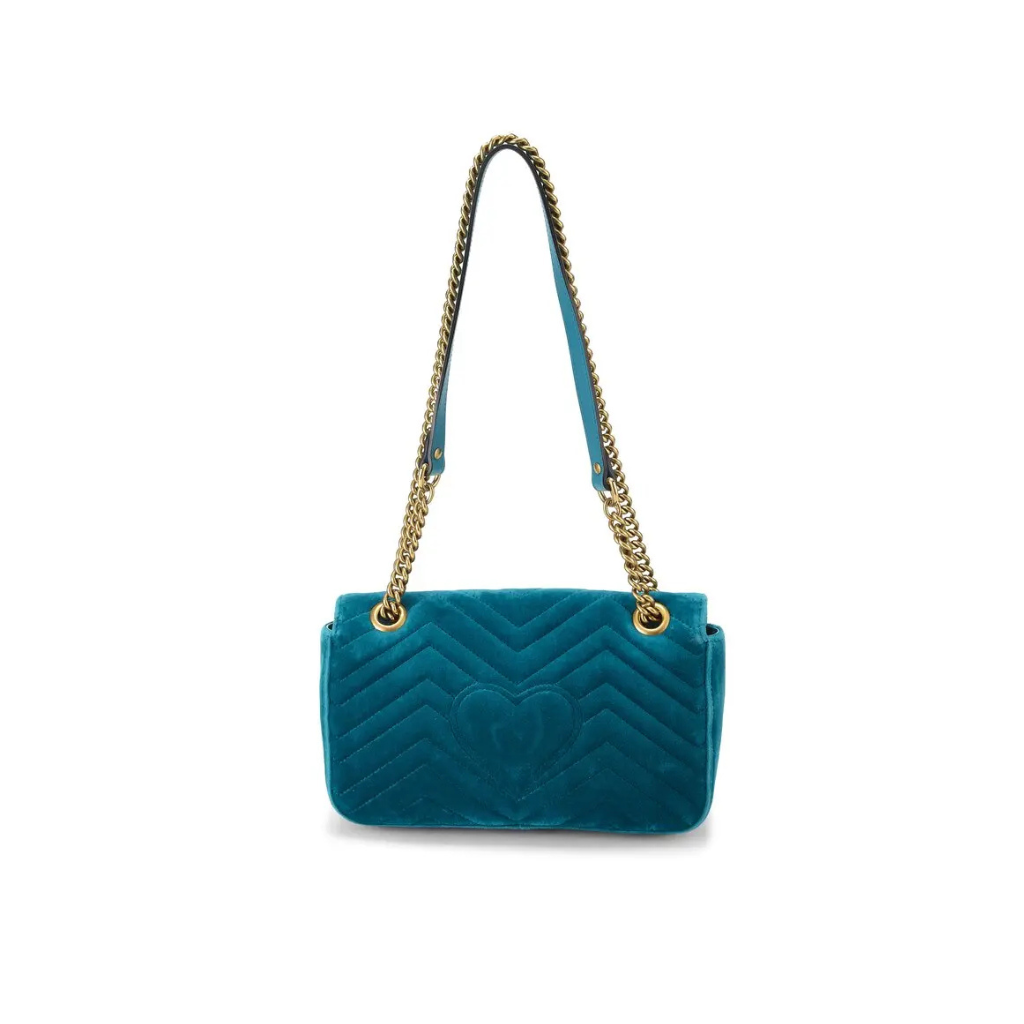 A teal blue quilted velvet shoulder bag with a gold-tone chain strap and a matching blue leather strap detail, shown against a plain white background.