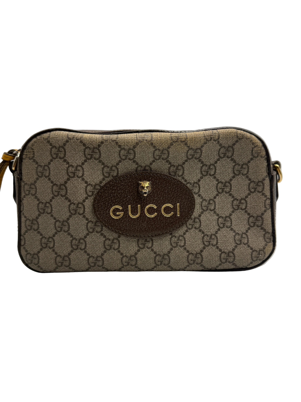 Front view of a Gucci Neo Classic camera bag in GG Supreme canvas with an oval brown leather patch, gold Gucci logo, and feline head hardware.