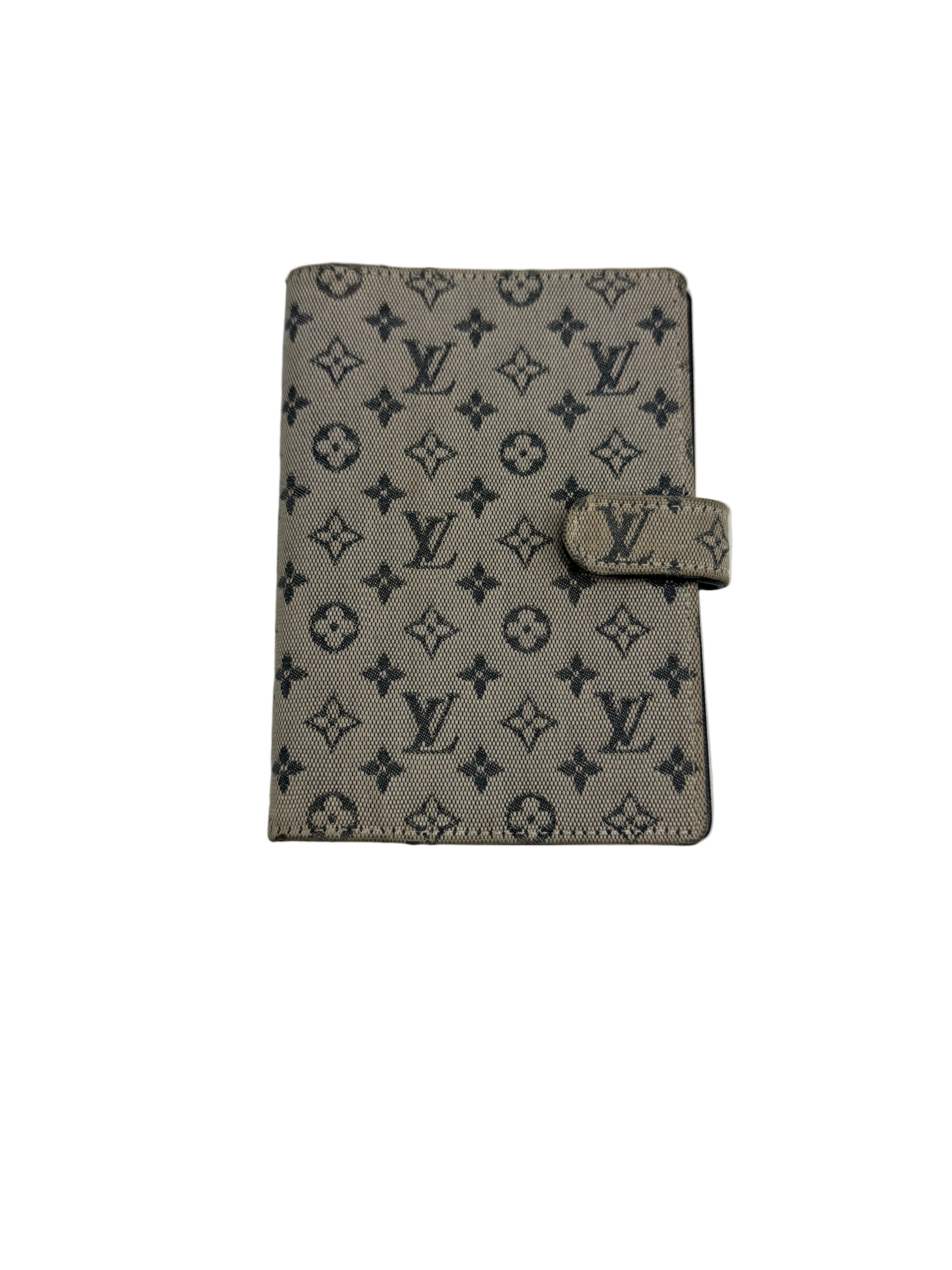 Front view of a closed Louis Vuitton Agenda PM planner cover in beige Monogram Mini canvas with tab snap closure.