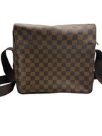 Front view of a Louis Vuitton Naviglio messenger bag in Damier Ébène canvas with a brown woven shoulder strap.