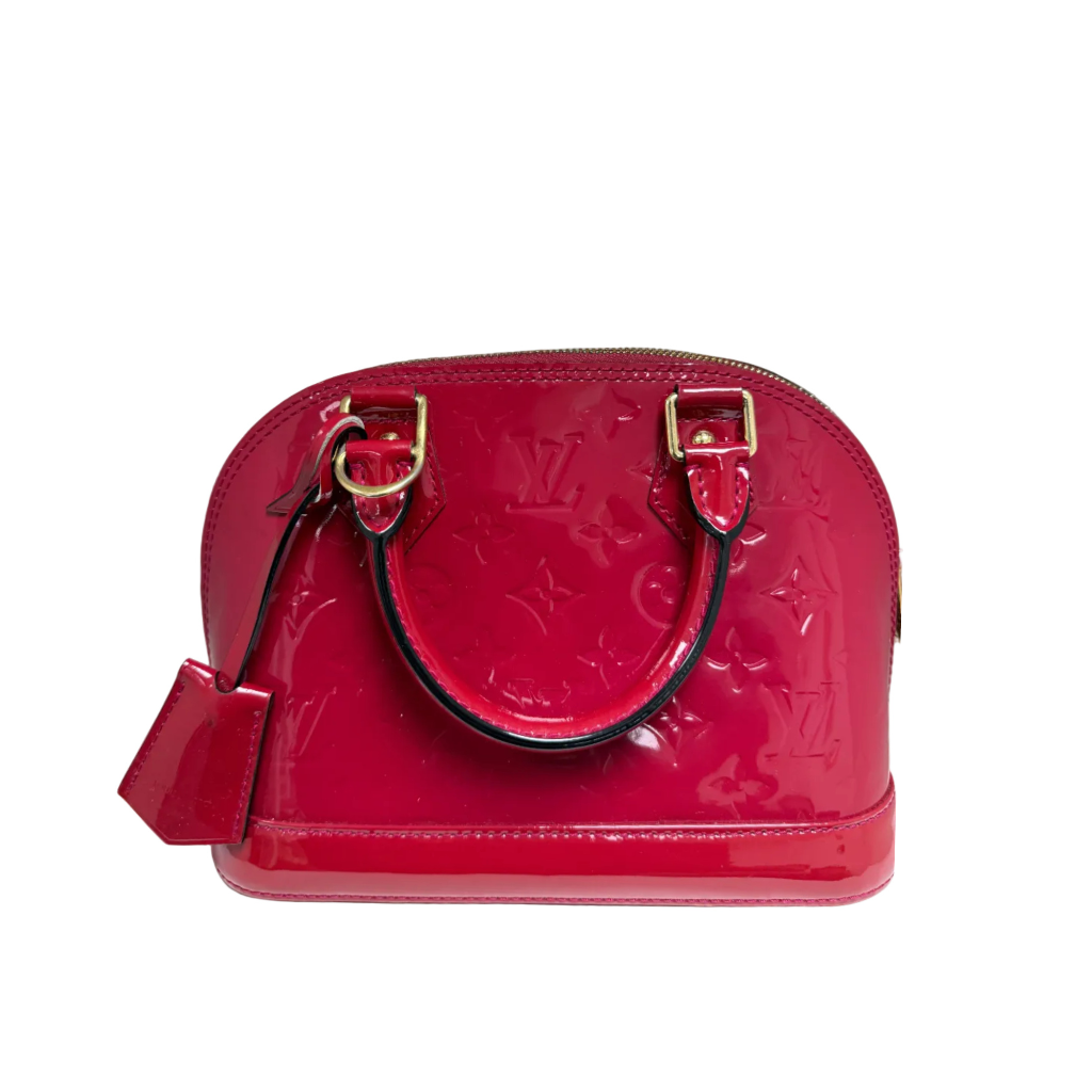 A Louis Vuitton glossy patent leather Alma handbag in a vibrant red color, featuring the embossed monogram pattern, gold-tone hardware, and a matching red leather hangtag, set against a plain white background.
