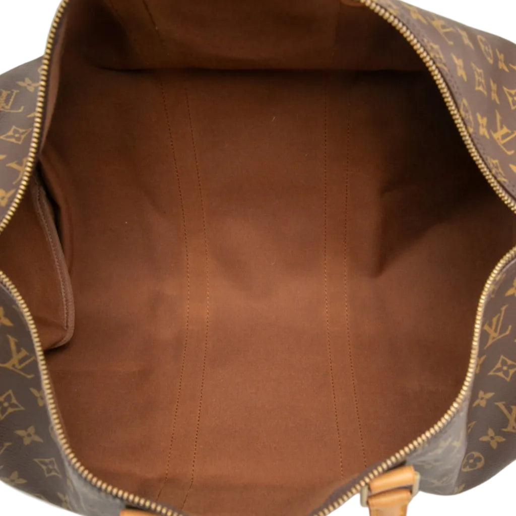The interior of a Louis Vuitton monogram duffel bag, showing a brown canvas lining and gold-tone zipper details.