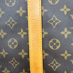 Close-up of a Louis Vuitton monogram canvas bag with a tan leather strap across the center.