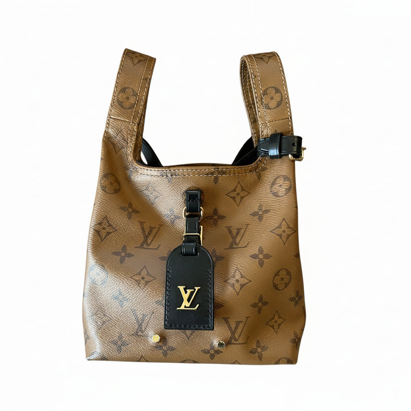 Louis Vuitton monogram patterned dog harness and tag on a textured surface