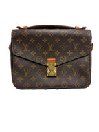 A Louis Vuitton monogram canvas shoulder bag in dark brown with gold-tone hardware and a top handle, photographed against a light gray background.