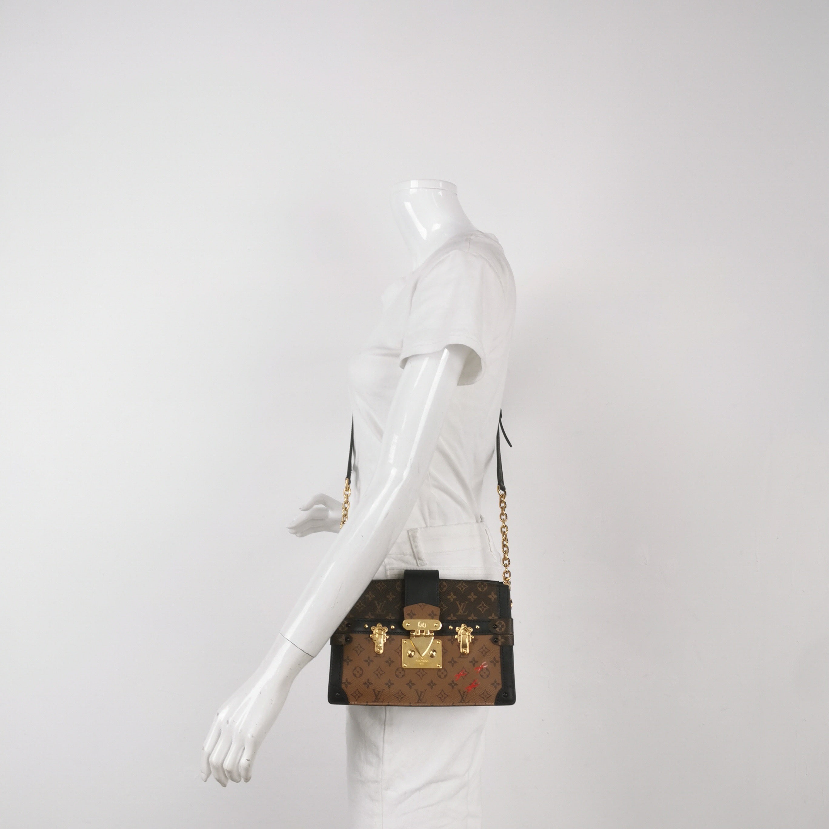 Mannequin wearing a preloved louis vuitton reverse monogram trunk clutch crossbody bag in great condition with gold hardware