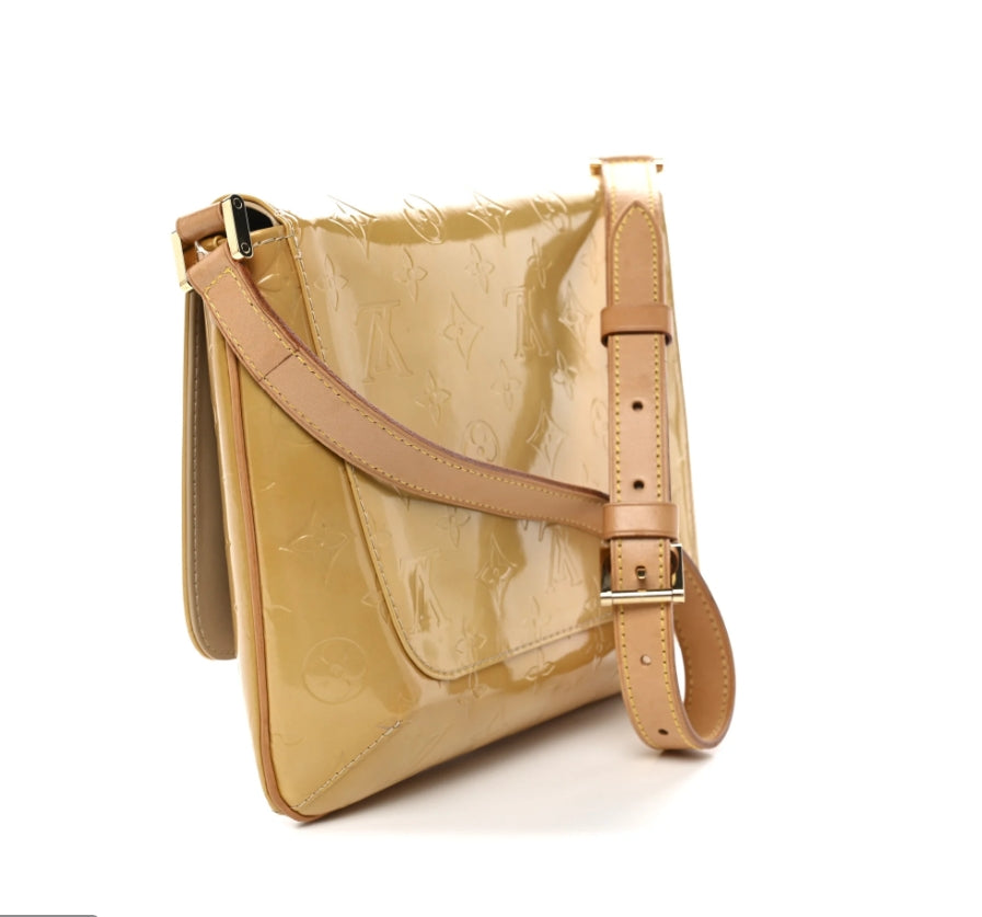A Louis Vuitton shoulder bag in beige patent leather with an embossed monogram pattern, featuring a matching leather strap with a silver-tone buckle, set against a plain white background.