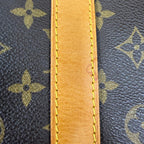 Close-up of a Louis Vuitton monogram canvas bag with a tan leather trim and yellow stitching.