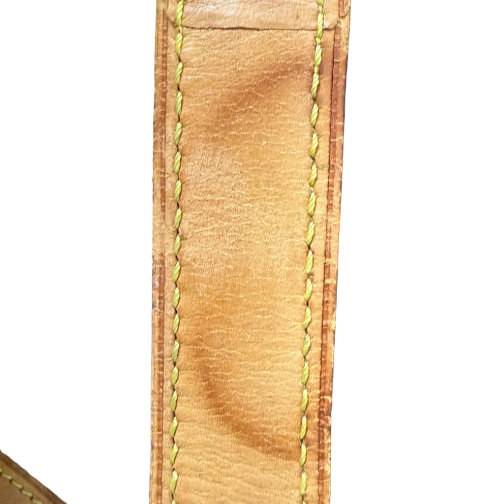 Close-up of a light tan leather strap with yellow stitching, showing a noticeable stain or discoloration in the center, set against a dark blue textured background.