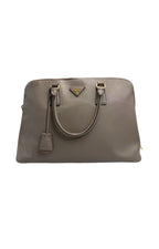 Front view of a Prada Saffiano Lux tote bag in Argilla taupe-grey leather with gold triangle logo and hanging clochette