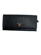 Front view of a Prada Saffiano leather continental flap wallet in black with gold-tone Prada Milano logo lettering